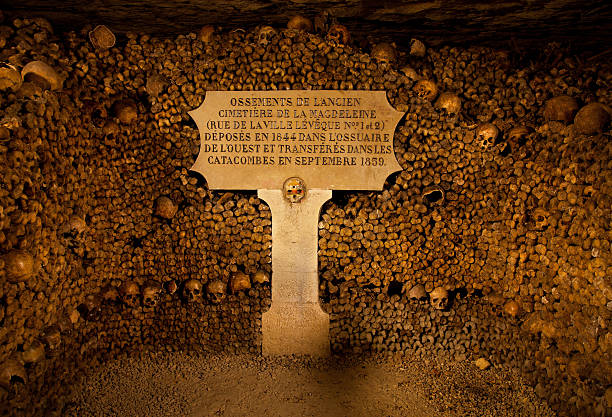 Piles of bones and skulls are arranged into a stack in the Paris' Catacombs.