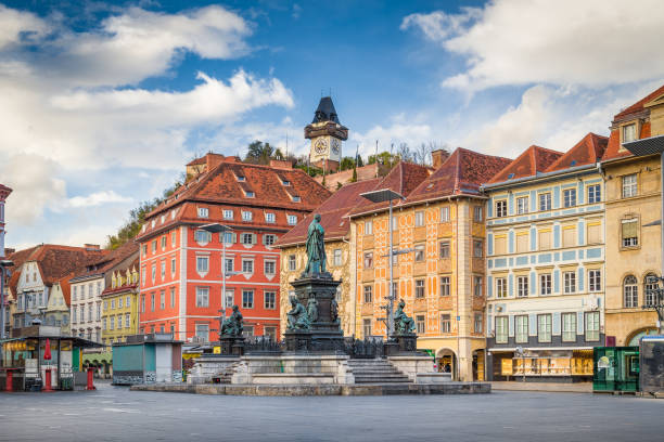 Classic view of the historic city of Graz with main square and famous Grazer clock tower in the background sitting on top of Schlossberg hill, Styria, Austria