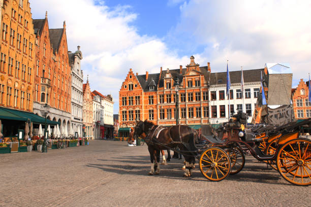 Old houses and horse carriages on Grote Markt square, medieval city Brugge, Belgium, Europe. UNESCO world heritage site